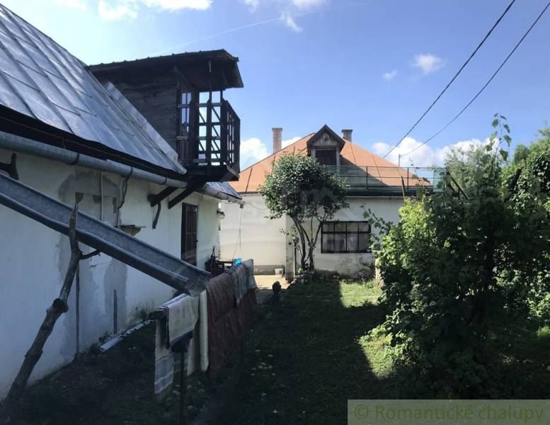 Rodinný dom v srdci Štiavnických vrchov, Štiavnické Bane. - Záhrada rodinného domu v Štiavnických Baniach s drevenou verandou a kvitnúcimi stromami.