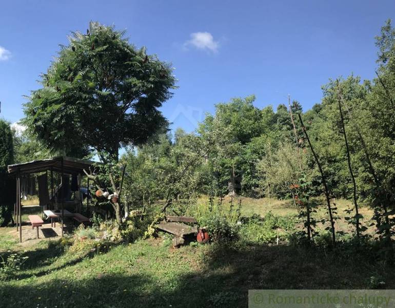 Rodinný dom v srdci Štiavnických vrchov, Štiavnické Bane. - Záhrada rodinného domu v Štiavnických Baniach, s altánkom a stromami pod modrou oblohou.