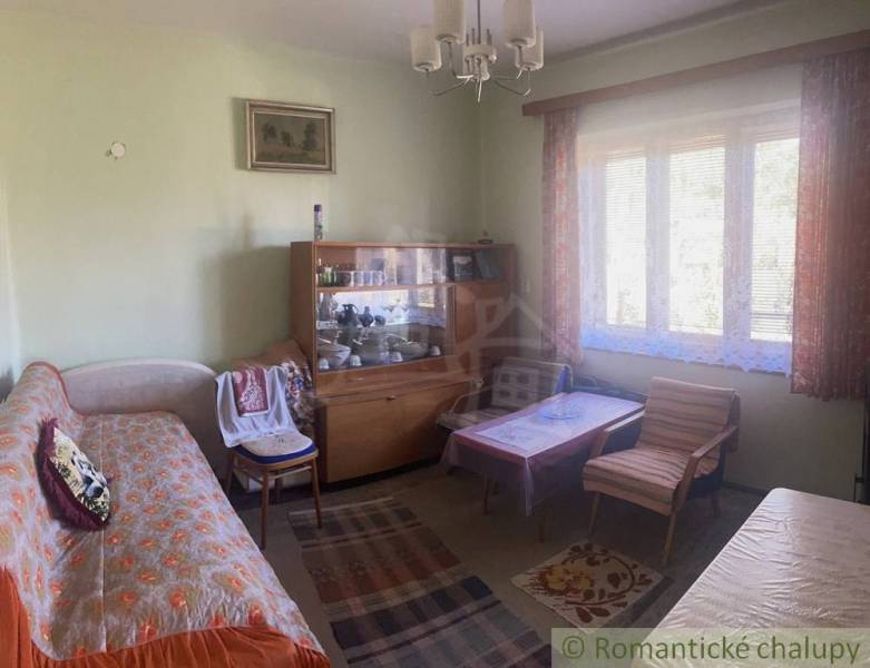 Rodinný dom v srdci Štiavnických vrchov, Štiavnické Bane. - Obývačka v rodinnom dome s pohovkou, vitrínou, kreslom a kobercom.