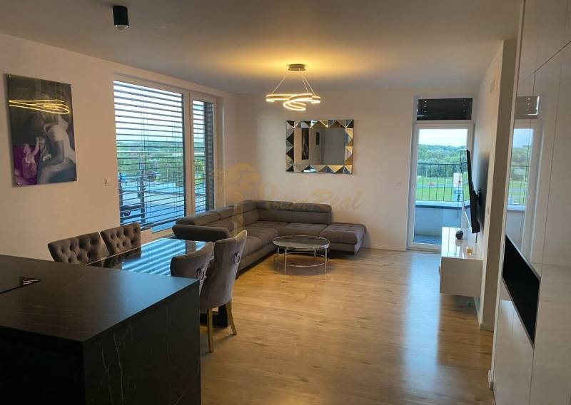 3-izb. byt, Zuzany Chalupovej, Petržalkou s veľkou terasou a saunou - Obývacia izba s rohovou sedačkou, jedálenským stolom a podlahou s dreveným dekorom.