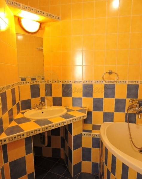 Nebytový priestor, Mikulášska, centrum mesta pod hradom - Kúpeľňa s oranžovo-modrými kachličkami, umývadlom a vaňou, v 1-izbovom byte na ulici Mikulášska.