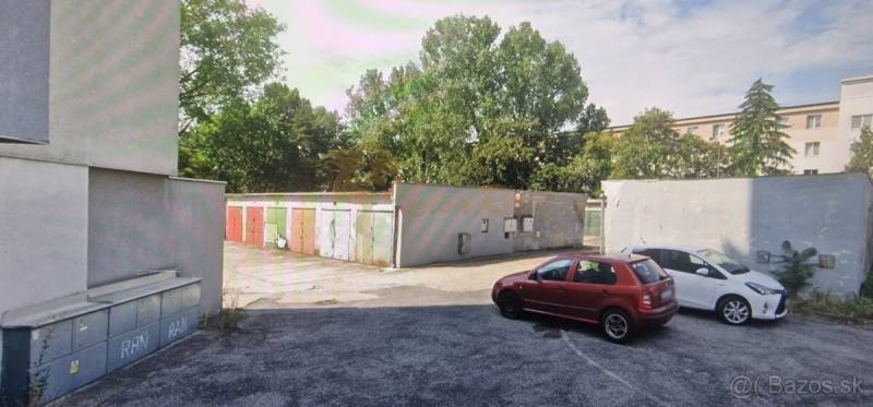 Garáž ul. Planét, Ružinov s pozemkom - Na ulici Planét sú zaparkované autá pred radom farebných garáží, obklopených stromami.