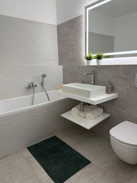 3-izb. byt, Martina Granca, Dúbravka, novostavba Pekná výhliadka - Kúpeľňa s vaňou, zrkadlom a umývadlom v 3-izbovom byte; tmavý koberec, svetlé obklady.