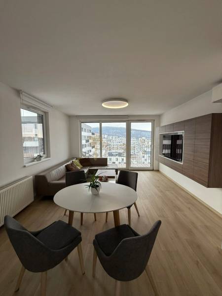 3-izb. byt, Martina Granca, Dúbravka, novostavba Pekná výhliadka - Obývačka v 3-izbovom byte s výhľadom, svetlou podlahou s dreveným dekorom a sedením.