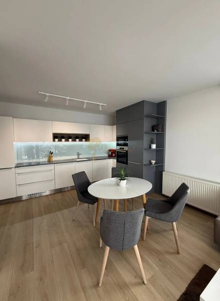 3-izb. byt, Martina Granca, Dúbravka, novostavba Pekná výhliadka - Kuchyňa v 3-izbovom byte s bielymi skrinkami, okrúhlym stolom a podlahou s dreveným dekorom.