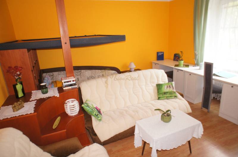 Veľký 1-izb. byt v tehlovom dome, Miletičova ul., Ružinov  - Obývacia izba v 1-izbovom byte s písacím stolom, pohovkou a podlahou s dreveným dekorom.