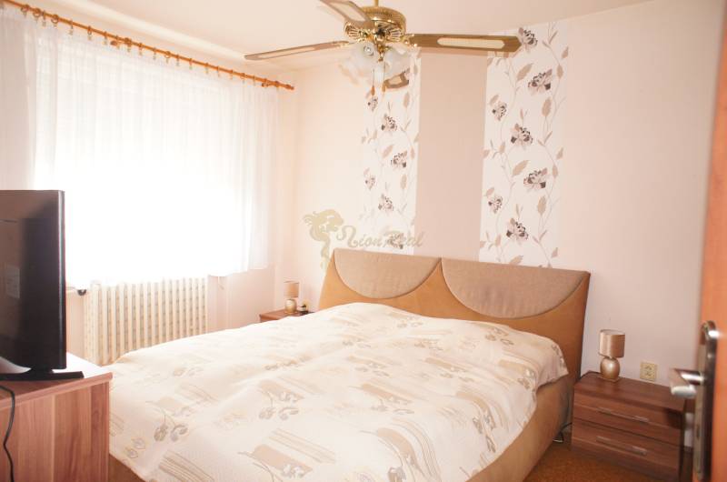 Rodinný dom v obci Čilížska Radváň s veľkým pozemkom - Spálňu v rodinnom dome zdobí posteľ, nočné stolíky a záclony na okne.