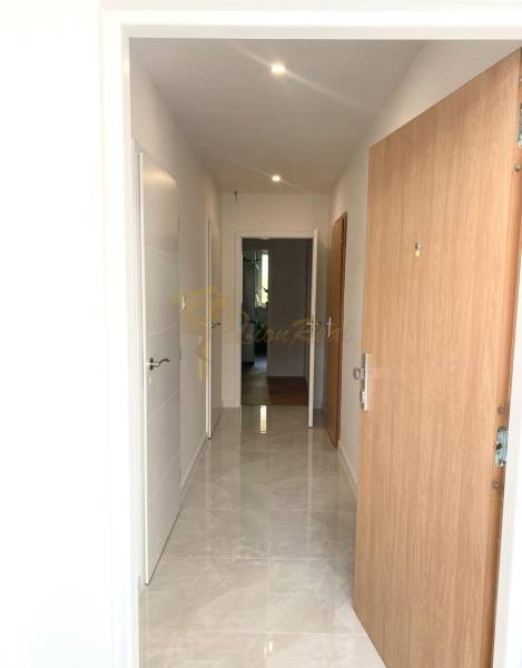 4-izb. byt, Cabanova ul., Dúbravka so samostatným vstupom - Úzka chodba so svetlými stenami a dlažbou, vchod na ulici Cabanova.