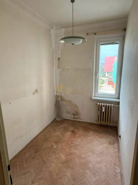 4-izb. byt, Martinčekova ul., Ružinov, 2.p./10, 2 x lodžia - Malá izba s podlahou s dreveným dekorom, poškodené steny a radiátor v 4-izbovom byte.