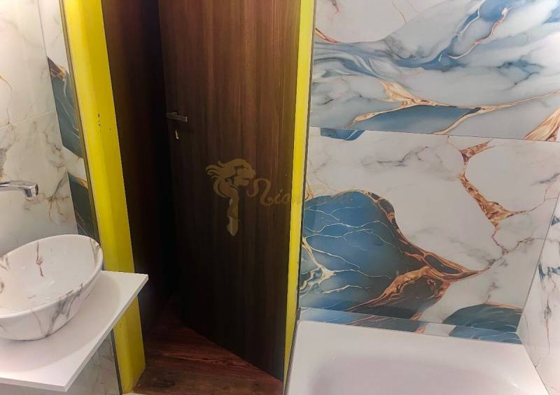 Garzónka M. Schneidra Trnavského, Dúbravka, veľká lodžia - Kúpeľňa v garsónke s modernou mozaikou a podlahou s dreveným dekorom.