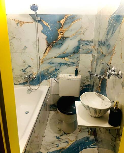 Garzónka M. Schneidra Trnavského, Dúbravka, veľká lodžia - Kúpeľňa v garsónke s vaňou a mramorovým umývadlom, obklady s modro-zlatým vzorom.