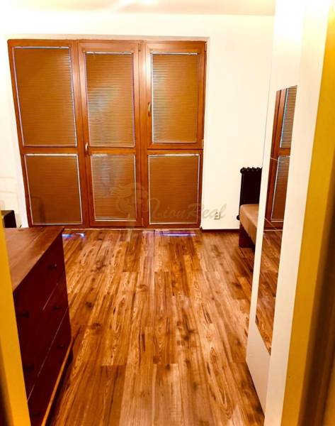 Garzónka M. Schneidra Trnavského, Dúbravka, veľká lodžia - Izba v garsónke s podlahou s dreveným dekorom a veľkými oknami s roletami.