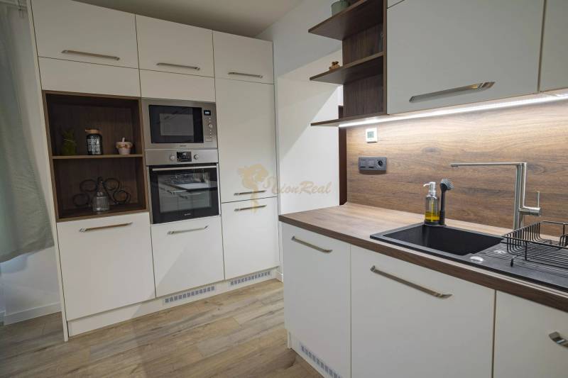 2,5 izb. byt, ul. Jelenia, Staré Mesto,tehlový dom, po rekonštrukcii - Kuchyňa s bielymi skrinkami, drevenou pracovnou doskou, vstavanými spotrebičmi v 3-izbovom byte na ulici Jelenia.