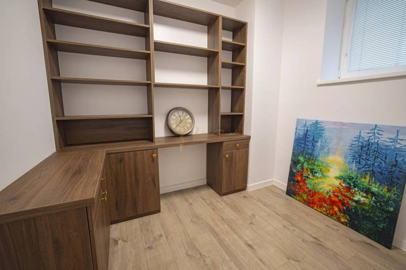 2,5 izb. byt, ul. Jelenia, Staré Mesto,tehlový dom, po rekonštrukcii - Na obrázku je prázdna drevená polica, hodiny a farebný obraz v 3-izbovom byte.