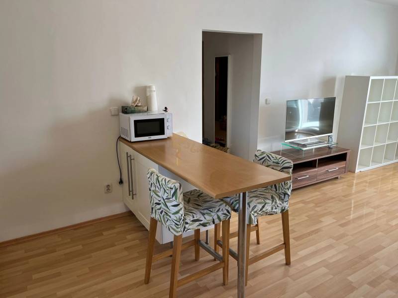 3-izb. byt, Palkovičova ul., Ružinov, lodžia, 4.p./12 - Kuchynský kút 3-izbového bytu s barovým pultom, stoličkami a podlahou s dreveným dekorom.