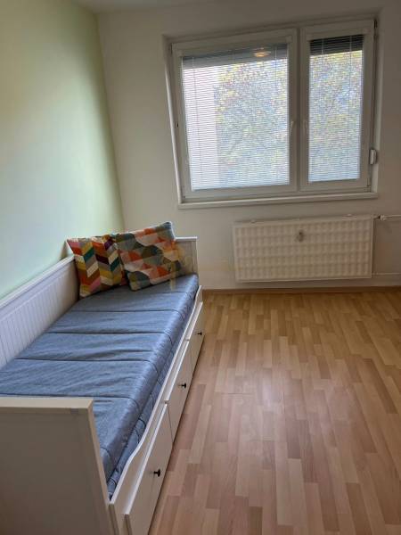 3-izb. byt, Palkovičova ul., Ružinov, lodžia, 4.p./12 - Jednoduchá izba s posteľou, oknom a podlahou s dreveným dekorom v 3-izbovom byte.