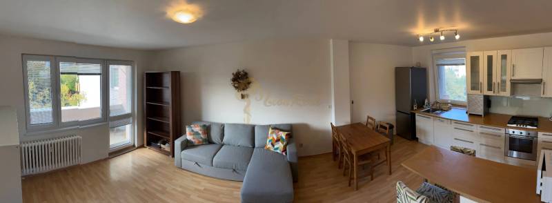 3-izb. byt, Palkovičova ul., Ružinov, lodžia, 4.p./12 - Priestranný obývací priestor s kuchyňou, jedálenským stolom a podlahou s dreveným dekorom.