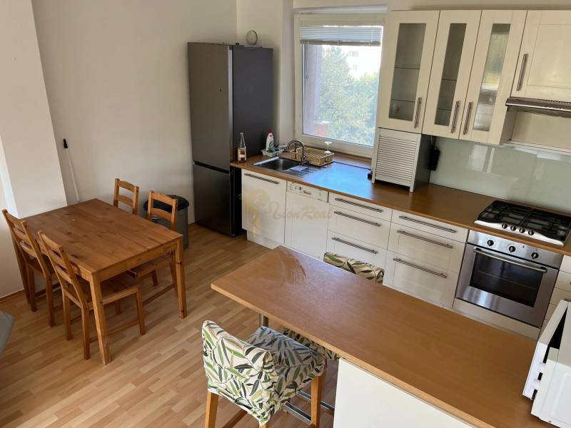 3-izb. byt, Palkovičova ul., Ružinov, lodžia, 4.p./12 - Kuchyňa s jedálenským stolom v 3-izbovom byte, podlaha s dreveným dekorom.