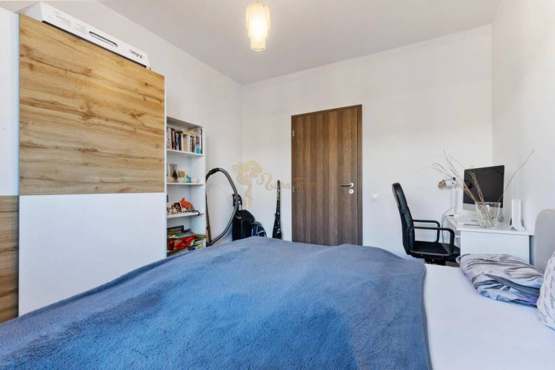 Novostavba 3-izb. bytu s parkovacím státím, ul.Hany Ponickej, Lamač - Spálňa v 3-izbovom byte s pracovným stolom, posteľou a skriňou s dreveným dekorom.