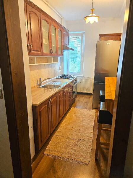 Prenájom pekný 3 izbový byt, Haburská ulica, Bratislava II. Ružinov - Kuchyňa v 3-izbovom byte s dreveným dekorom a svetlým kobercom.