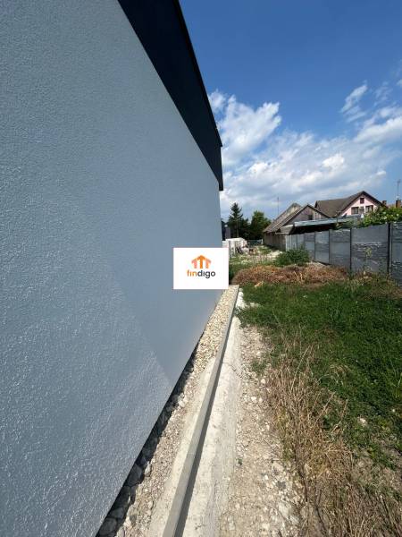 PREDAJ - Rodinný dom v obci Žíharec - Stena rodinného domu v Žihárci s priľahlým pozemkom pod modrou oblohou.