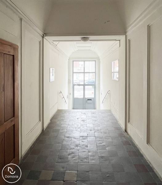 Exkluzívne | Na predaj výnimočný 2i byt pri Trnavskom mýte  - Chodba s dlaždicami a bielymi stenami vedie k presklenej bráne na ulici Vajnorská.