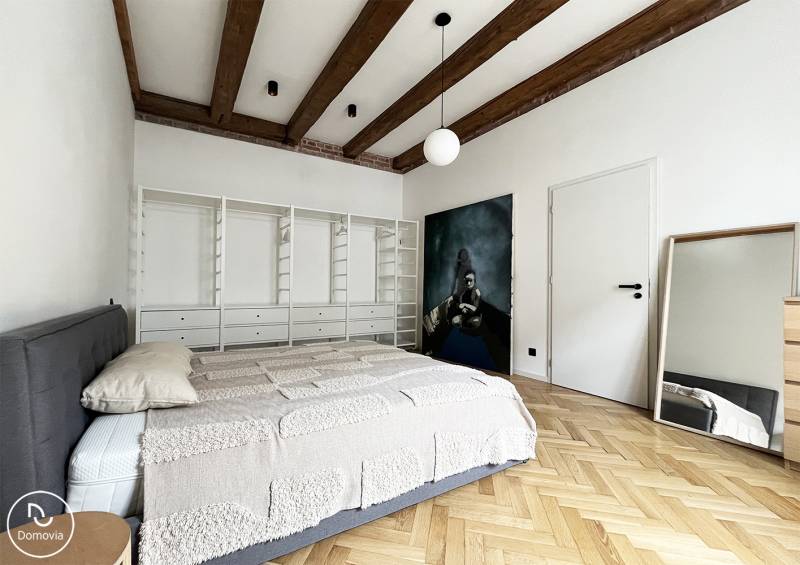 Exkluzívne | Na predaj výnimočný 2i byt pri Trnavskom mýte  - Spálňa v 2-izbovom byte s drevenými trámami a zrkadlom na ulici Vajnorská.