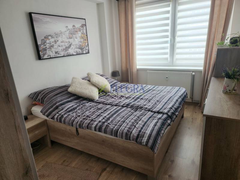 Na prenájom  1,5 izbový byt  Učňovská ulica Šaca - Spálňa v 2-izbovom byte s podlahou s dreveným dekorom, dvojposteľou a dekoráciou.