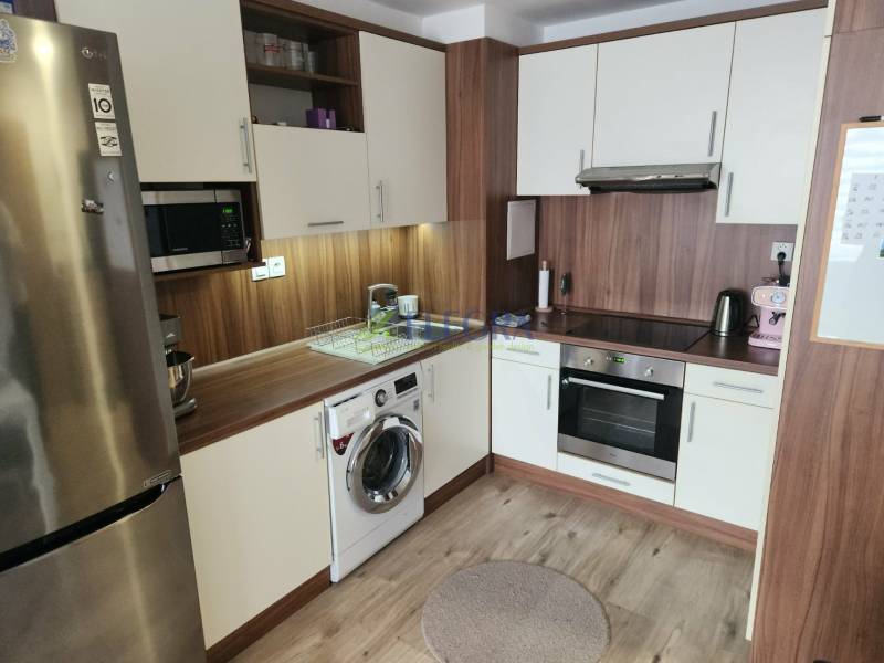 Na prenájom  1,5 izbový byt  Učňovská ulica Šaca - Kuchyňa v 2-izbovom byte s podlahou s dreveným dekorom, sporákom a chladničkou.