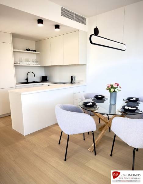 Prenájom 3-izbový byt s loggiou, SKY PARK, Bratislava - Kuchynský kút s bielymi skrinkami, skleneným stolom a podlahou s dreveným dekorom v 3-izbovom byte.