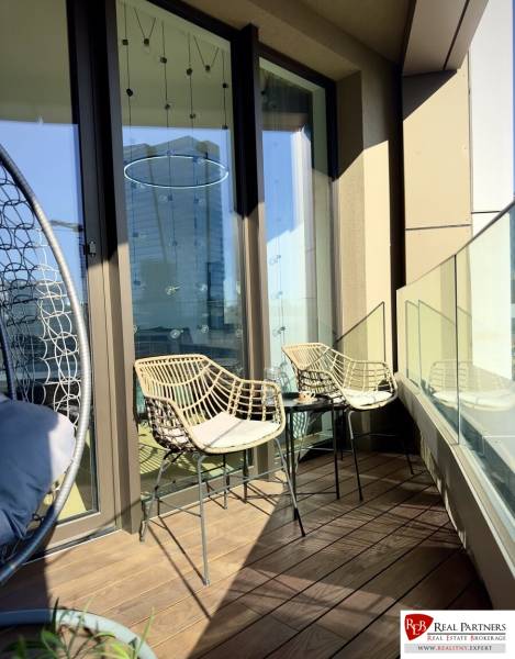 Prenájom 3-izbový byt s loggiou, SKY PARK, Bratislava - Balkón v 3-izbovom byte s ratanovými stoličkami a skleneným zábradlím.
