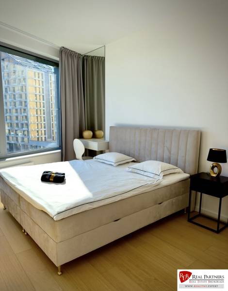 Prenájom 3-izbový byt s loggiou, SKY PARK, Bratislava - Spálňa v 3-izbovom byte s posteľou, nočným stolíkom a podlahou s dreveným dekorom.