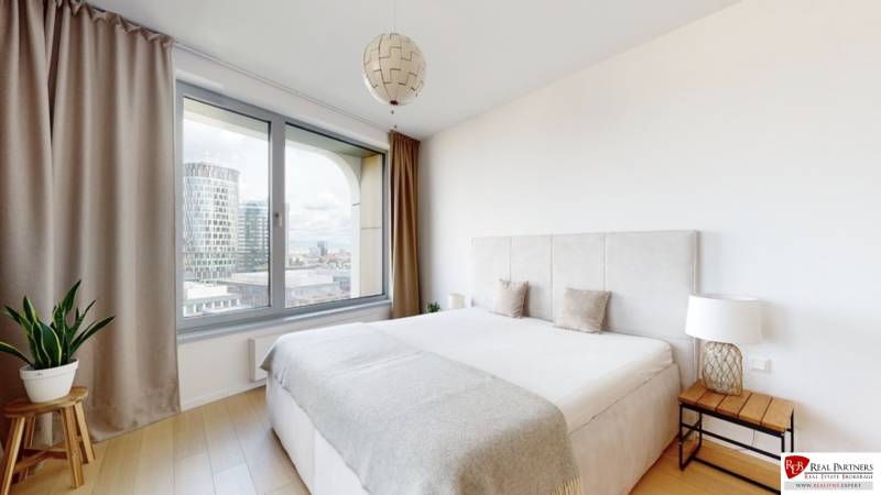 Prenájom 3-izbový byt s terasou, SKY PARK, Bratislava - Spálňa v 3-izbovom byte s veľkým oknom, závesmi a podlahou s dreveným dekorom.