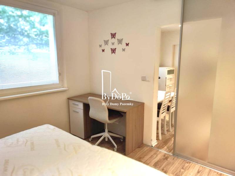 2-izbový byt, 49 m2, Cabanova ul., Bratislava - Dúbravka - Izba v 2-izbovom byte na ulici Cabanova, písací stolík, stolička, nástenné dekorácie.