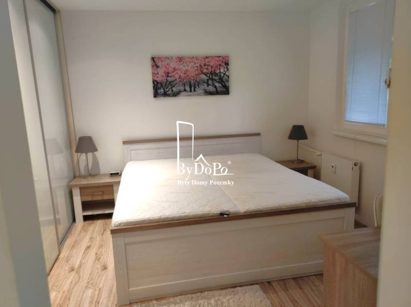 2-izbový byt, 49 m2, Cabanova ul., Bratislava - Dúbravka - Spálňa so šedou posteľou v 2-izbovom byte na ulici Cabanova, drevená podlaha.