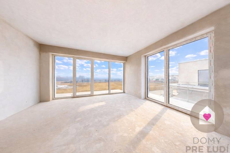 3i. BYT S VLASTNÝM TEP. ČERPADLOM + KLIMATIZÁCIA A EXTERIÉROVÉ ŽALÚZIE - Priestranná izba v 3-izbovom byte s veľkými oknami a výhľadom na krajinu.