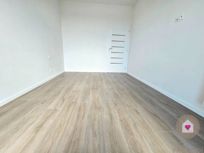 3i. BYT S VLASTNÝM TEP. ČERPADLOM + KLIMATIZÁCIA A EXTERIÉROVÉ ŽALÚZIE - Izba v 3-izbovom byte s drevenou podlahou a bielymi stenami.