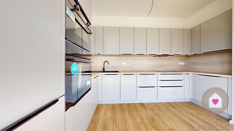 3i. BYT S VLASTNÝM TEP. ČERPADLOM + KLIMATIZÁCIA A EXTERIÉROVÉ ŽALÚZIE - Kuchyňa v 3-izbovom byte s drevenou podlahou a vstavanými spotrebičmi.