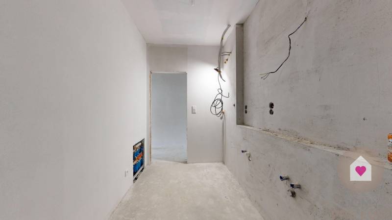 3i. BYT S VLASTNÝM TEP. ČERPADLOM + KLIMATIZÁCIA A EXTERIÉROVÉ ŽALÚZIE - Nedokončená kuchyňa v 3-izbovom byte s bielymi stenami a voľnými káblami.