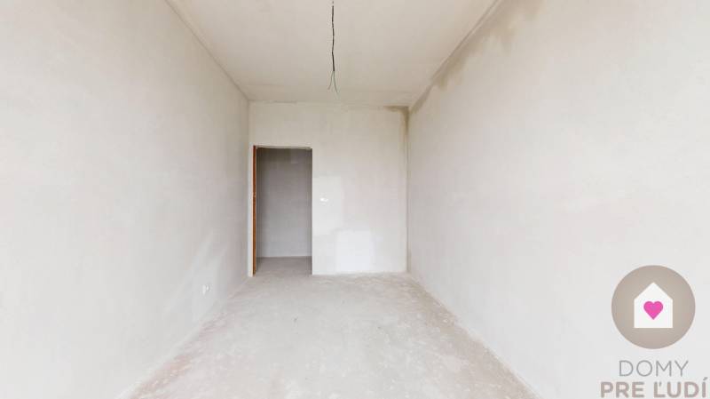 3i. BYT S VLASTNÝM TEP. ČERPADLOM + KLIMATIZÁCIA A EXTERIÉROVÉ ŽALÚZIE - Prázdna miestnosť v 3-izbovom byte s bielymi stenami a betónovou podlahou.