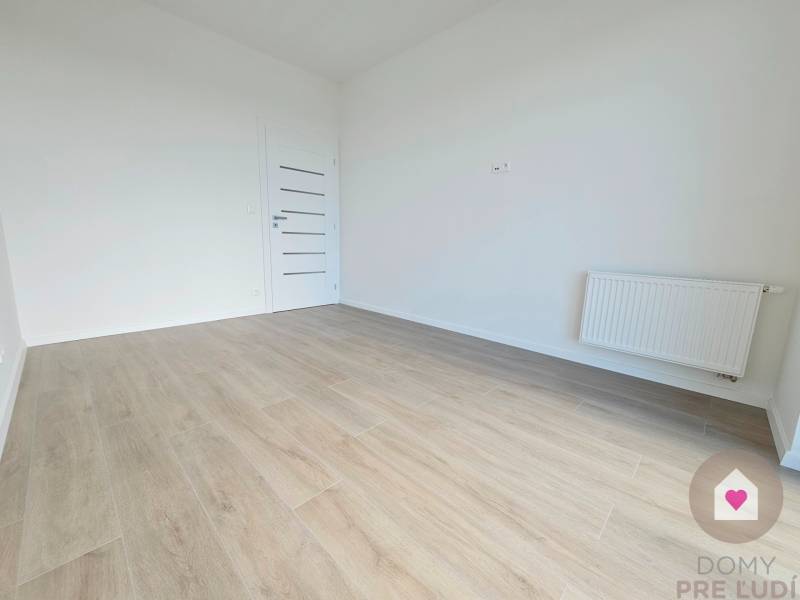 3i. BYT S VLASTNÝM TEP. ČERPADLOM + KLIMATIZÁCIA A EXTERIÉROVÉ ŽALÚZIE - Izba v 3-izbovom byte s drevenou podlahou a bielymi stenami.