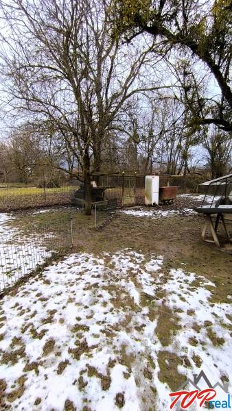 Pekný stavebný pozemok v obci Krásnohorské Podhradie - Pozemok na Mierovej ulici v Krásnohorskom Podhradí s trávou a snehom, vhodný na bývanie.