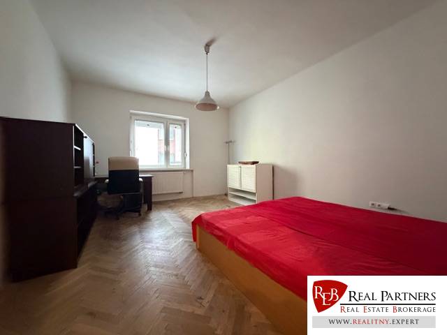 Predaj 3 izbový byt, 86 m2, Francisciho ul, Staré mesto, BAI . - Spálňa v 3-izbovom byte s posteľou, písacím stolom a podlahou s dreveným dekorom.