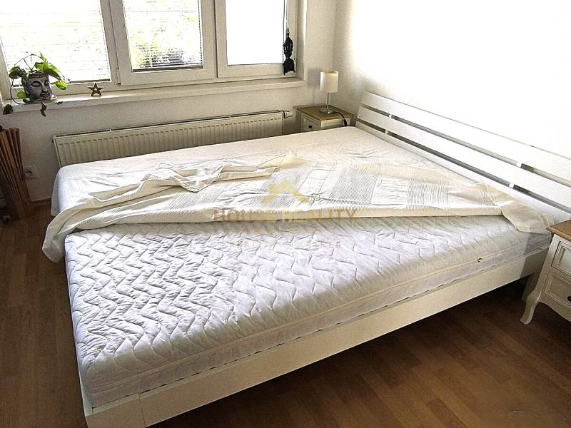 Novostavba s parkovaním 2 izbový byt, Jégeho ulica, BA II. Ružinov - Svetlá spálňa s bielou posteľou a podlahou s dreveným dekorom v 2-izbovom byte.