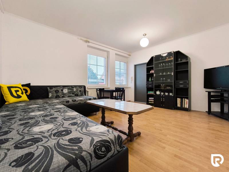 | 2i byt v rodinnom dome | 65 m | Bratislavská | Záhorská B. - Obývacia izba v rodinnom dome s pohovkou, poličkami, televízorom a podlahou s dreveným dekorom.