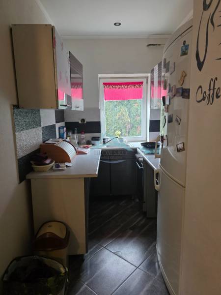 Útulný rodinný dom v tichej obci Hont, Maďarsko - Úzka kuchyňa s čiernobielymi skrinkami a veľkou bielou chladničkou v rodinnom dome.