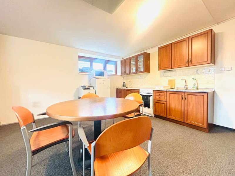 PRENÁJOM- KANCELÁRSKÝ PRIESTOR -120m2- KOMÁROVSKÁ - Kuchyňa v rodinnom dome s jedálenským stolom, stoličkami a kuchynskou linkou s dreveným dekorom.