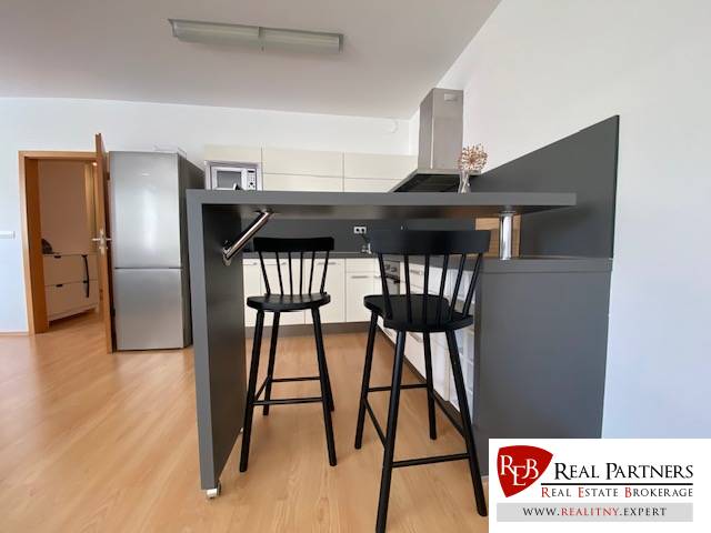 Prenájom 2 izbový 78 m2 + 30 m2 terasa,novostavba Koliba,zariadený - Kuchyňa 2-izbového bytu s barovým pultom, stoličkami a podlahou s dreveným dekorom.