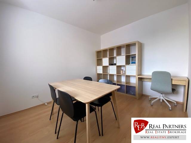 Prenájom 2 izbový 78 m2 + 30 m2 terasa,novostavba Koliba,zariadený - Interiér 2-izbového bytu s čiernymi stoličkami, pracovným stolom a podlahou s dreveným dekorom.