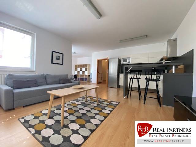 Prenájom 2 izbový 78 m2 + 30 m2 terasa,novostavba Koliba,zariadený - Obývacia izba v 2-izbovom byte s podlahou s dreveným dekorom a rozkladacím gaučom.